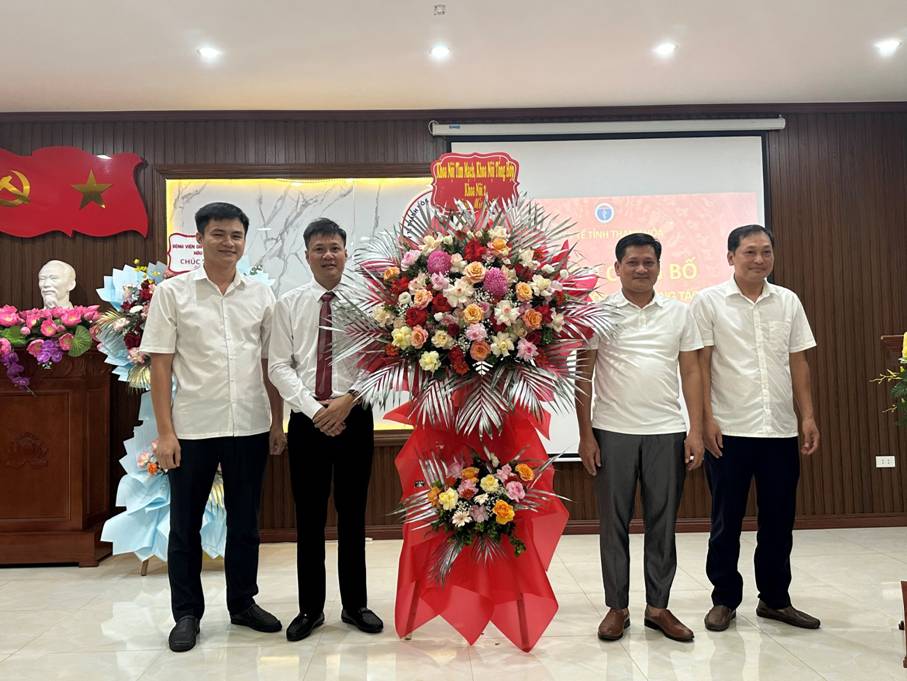 A group of men standing in front of a large red and white display

Description automatically generated