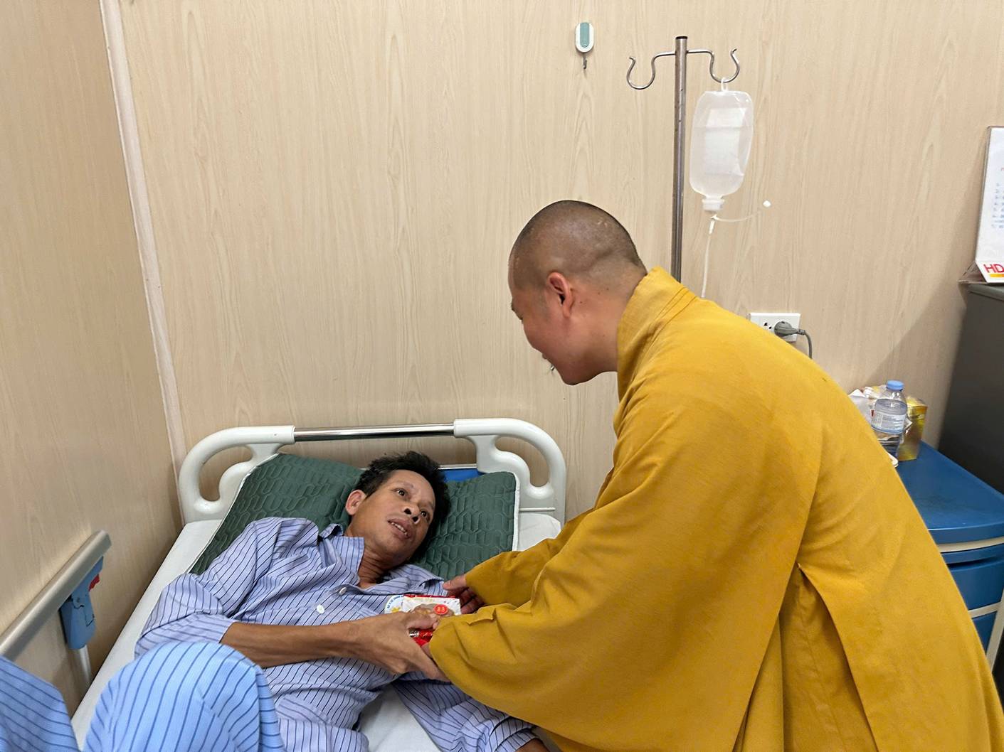 A person in a yellow robe holding a person's hand in a hospital bed

AI-generated content may be incorrect.